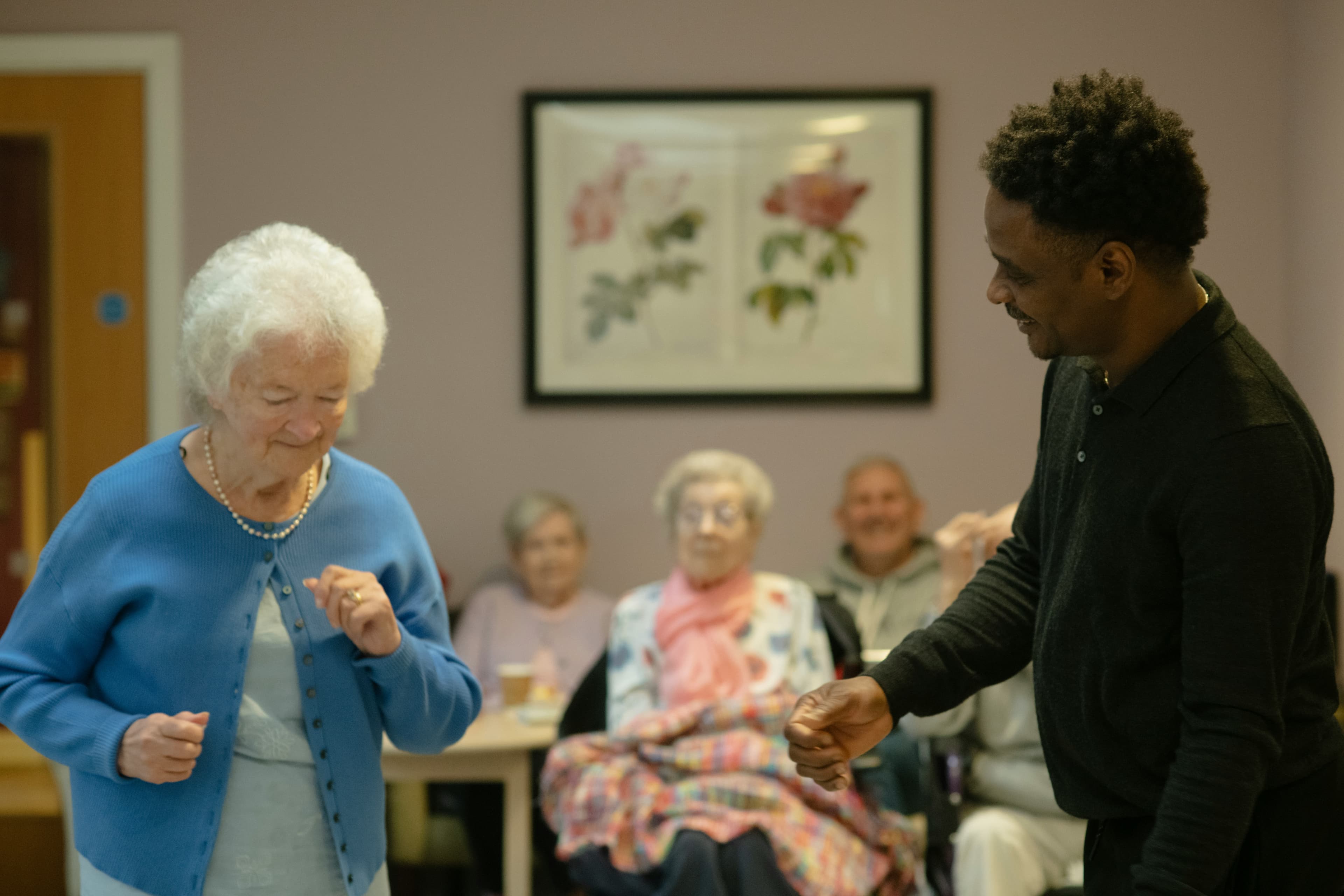 Older adult and caregiver sharing a dance in a group activity room